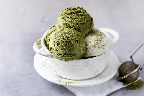 绿色的茶水日本抹茶和椰子冰乳霜采用白色的碗向一灰色的英语字母表的第2个字母