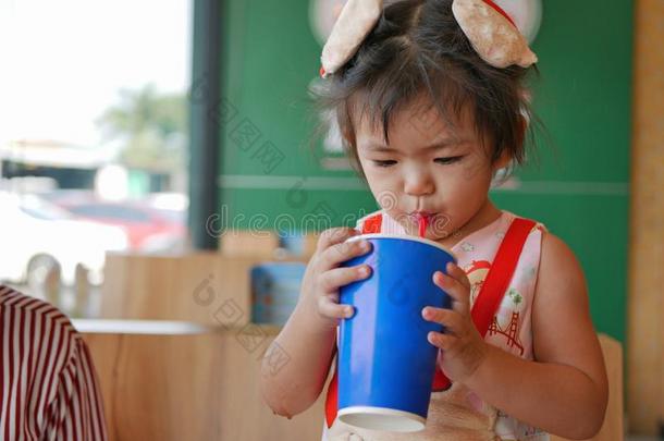 小的亚洲人婴儿女孩喝饮料<strong>大</strong>的<strong>杯子</strong>关于含二氧化碳的s关于t喝