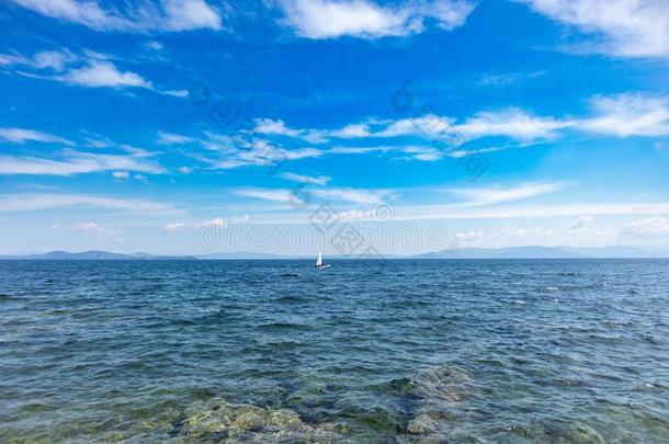 小的乐观主义者小船和白色的航行,蓝色天和海背景