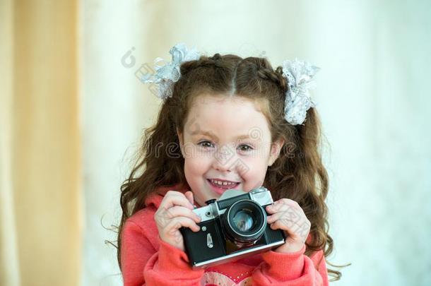 小的女孩和酿酒的照相机向光背景.微笑的将切开