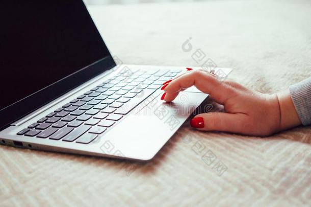 女人手和红色的钉子向便携式电脑键盘,女士使用便携式电脑