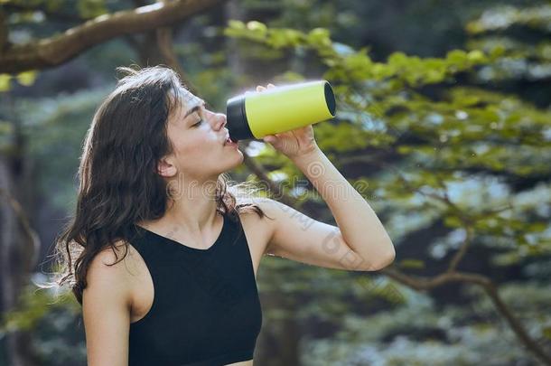 <strong>健康</strong>的<strong>健康</strong>女孩喝饮料水从<strong>绿色</strong>的瓶子采用森林