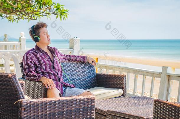 男人有样子的在海和收听的向音乐在海front台阶