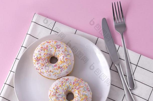 美味的油炸圈饼向指已提到的人盘子和餐巾和餐具在粉红色的波黑