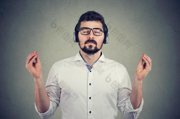 男人采用耳机和关闭着的眼睛listen采用g向音乐和梅迪塔