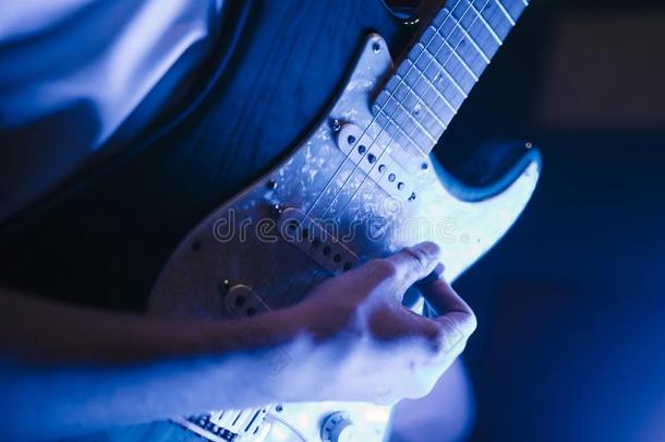 男人演奏吉他在室内特写镜头向指已提到的人照片