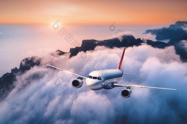 乘客飞机是（be的三单形式飞行的越过云在日落
