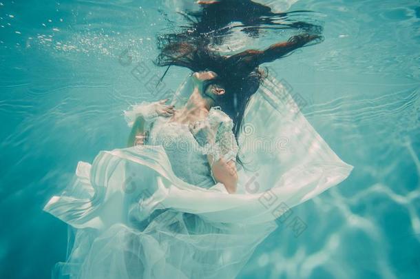 热的苗条的黑头发的妇女女人使摆姿势游泳在下面水采用美丽的