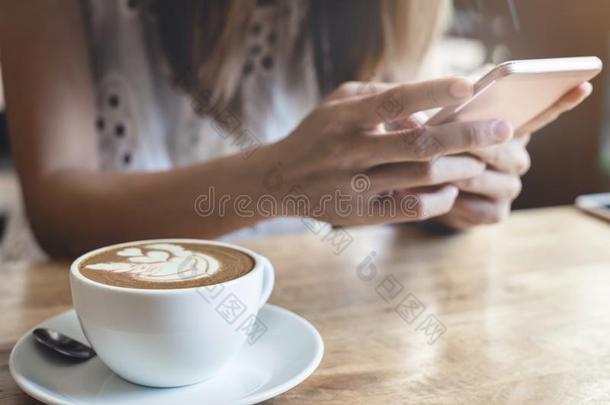 年幼的女人使用聪明的电话采用咖啡豆商店