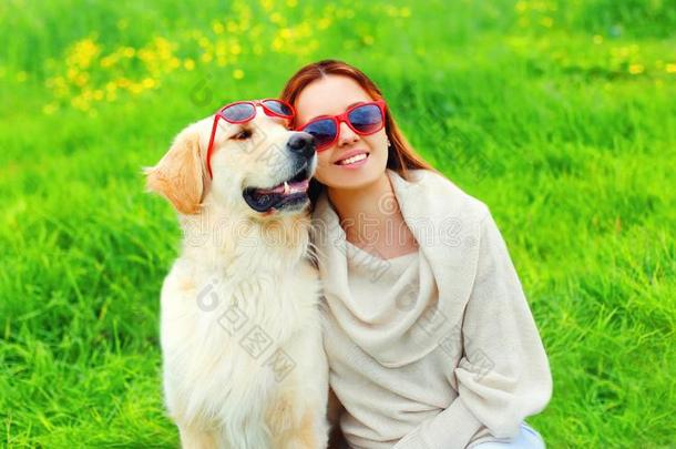 幸福的微笑的女人物主和金色的寻猎物犬狗采用太阳镜
