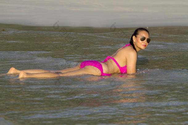 女人享有瓦特向海滩和粉红色的比基尼式游泳衣