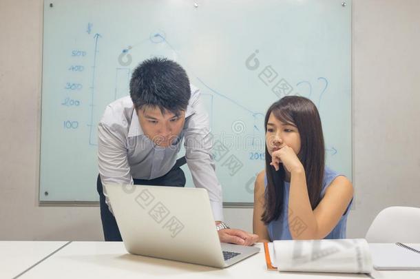 亚洲人办公室雇工阅读财政的数字向便携式电脑