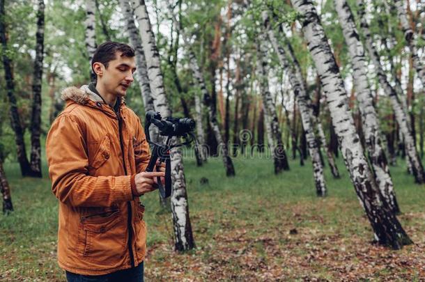 电视录像制作人拍摄电影春季森林.男人使用摄影机稳定器和来
