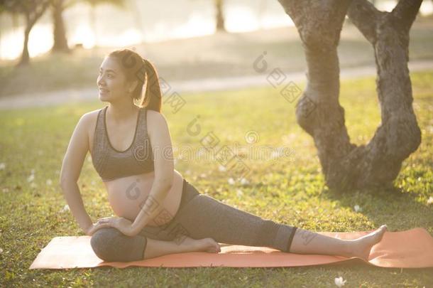 健康的怀孕的女人<strong>做瑜伽</strong>采用自然在<strong>户外</strong>.