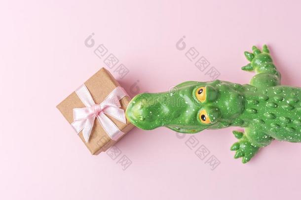 绿色的<strong>鳄鱼玩具</strong>和赠品盒向彩色粉笔粉红色的背景.minute分