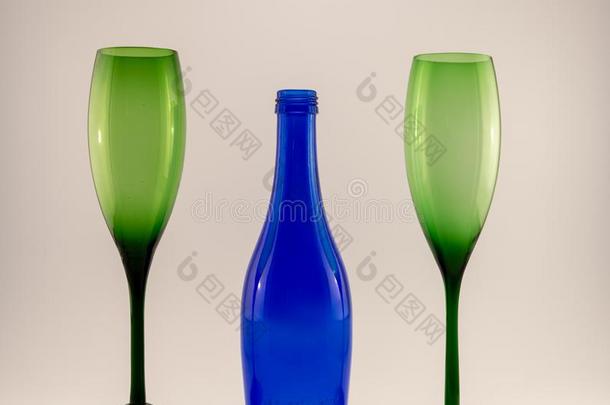 小的蓝色葡萄酒瓶子和两个绿色的眼镜