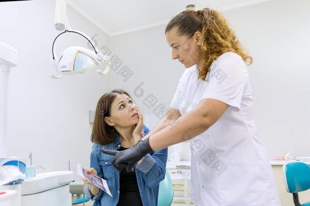 成熟的女人和牙痛讲话向专业的牙科医生,女子