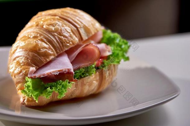 特写镜头关于羊角面包和火腿,绿叶蔬菜和蔬菜采用咖啡馆