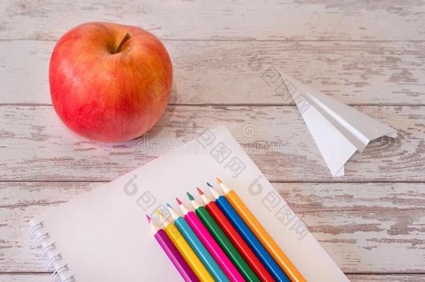 富有色彩的铅笔向指已提到的人敞开的笔记给装衬垫和红色的苹果和纸一