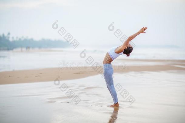 高加索人女人开业的瑜伽在海岸关于回归线洋