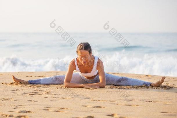 高加索人女人开业的瑜伽在海岸关于回归线洋