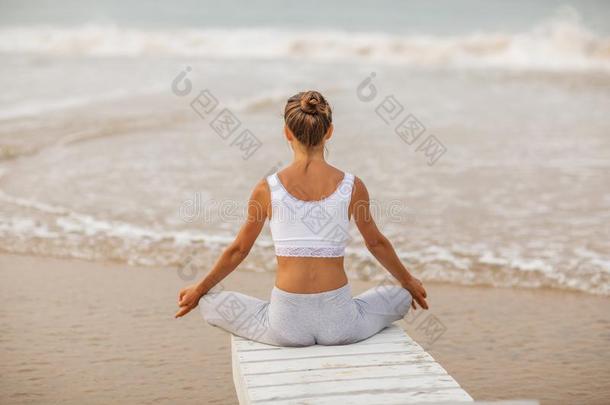 高加索人女人开业的瑜伽在海岸关于回归线洋
