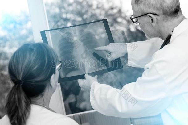 两个医生仔细检查字母x-射线报告;黑的和白色的