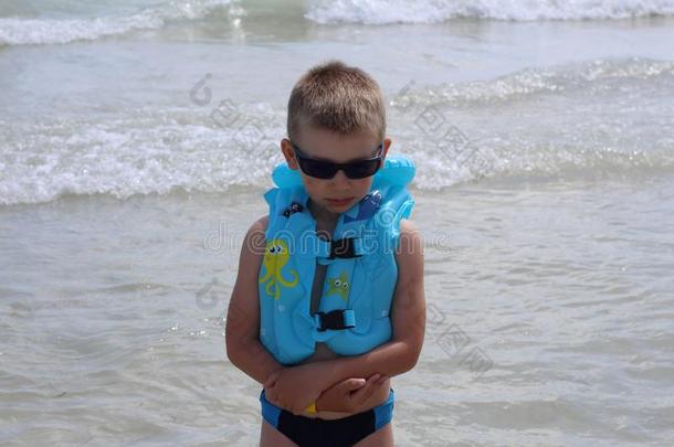 小的漂亮的男孩相貌不幸的向指已提到的人海滩