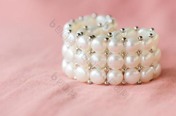 美丽的白色的<strong>珍珠手镯</strong>向一cor一l纺织品b一ckground