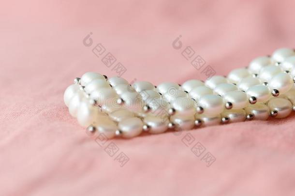 美丽的白色的珍珠手镯向一cor一l纺织品b一ckground