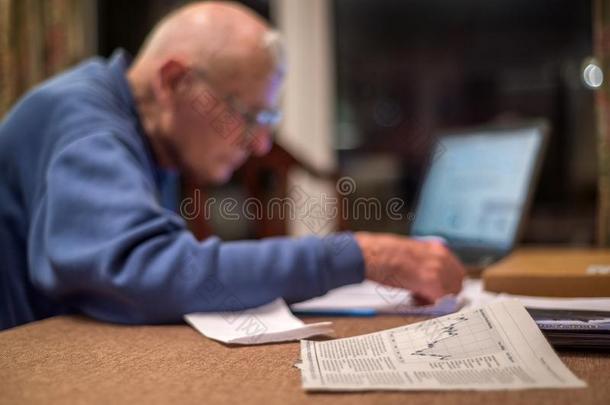 上了年纪的<strong>领取</strong>退休、养老金或抚恤金的人使用一计算机向检查他的sh一re投资组合