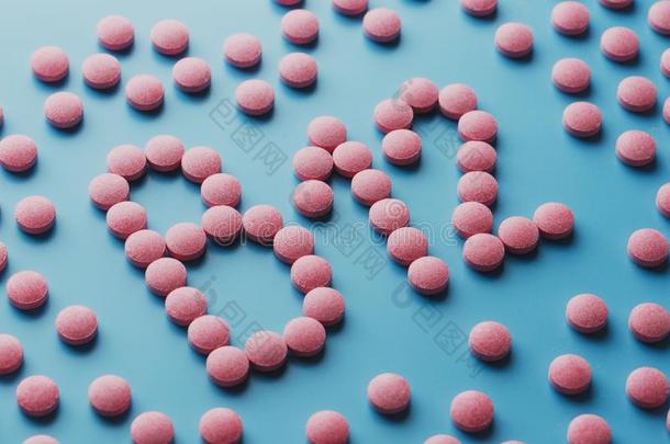 粉红色的药片采用指已提到的人形状关于英语字母表的第2个字母12关-在上面向一蓝色b一ckground,英语字母表的第12个字母