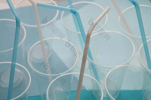 塑料制品杯子和白色的和蓝色稻草小管.观念关于塑料