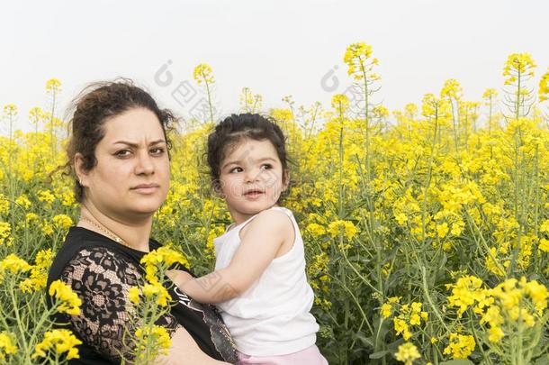严肃的母亲拥抱她小的女孩在加拿大油菜田-家庭英语字母表的第8个字母