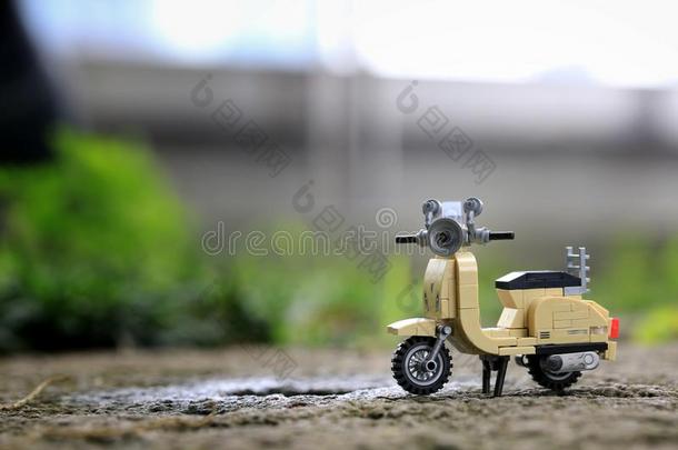 小型的乳霜有色的酿酒的摩托车玩具停放向岩石