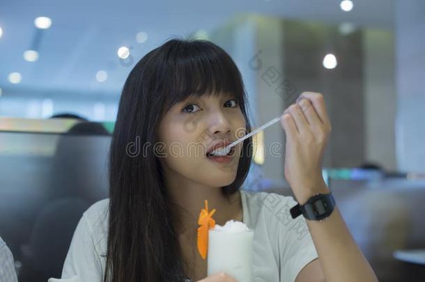 亚洲人女人享有和新鲜的椰子水果汁刨冰采用指已提到的人餐馆