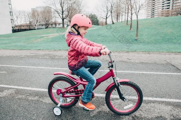 学龄前<strong>儿童</strong>女孩骑马粉<strong>红色</strong>的自行车自行车采用头盔向后院