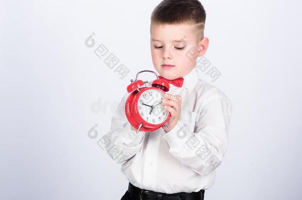 放置在上面惊恐钟.小孩小的男孩拿住<strong>红色</strong>的钟.它是（be的三单形式时间.