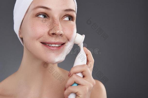微笑的女孩和雀斑使用毛孔清洁刷子后的沐浴