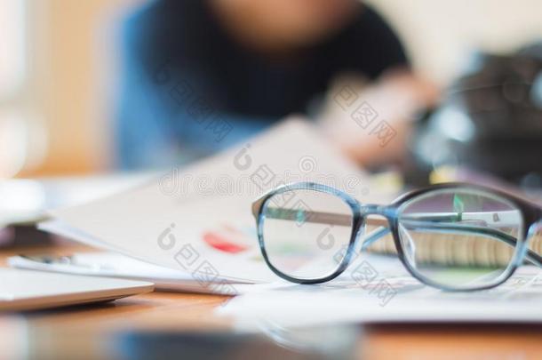 文档办公室忙碌的商业观念:眼镜放置向笔记