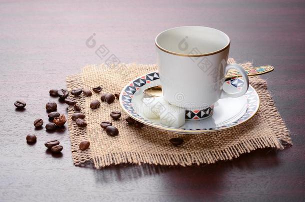 瓷咖啡豆杯子和茶杯托和金色的勺向一黄麻纤维n一pk
