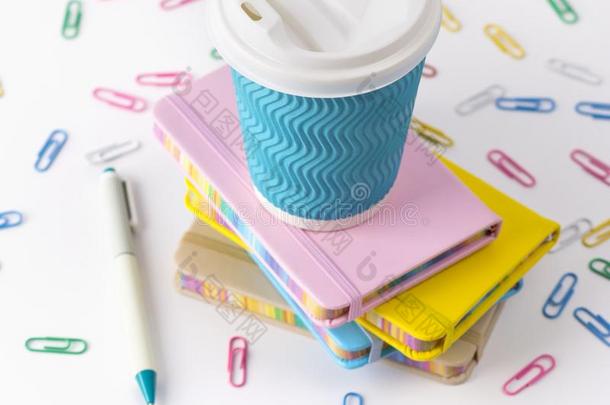 蓝色纸咖啡豆杯子,笔和记事本隔离的向白色的后面