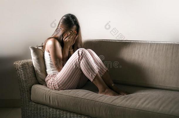 年幼的悲哀的和情绪低落的女人采用睡衣在在家长沙发椅cry采用g