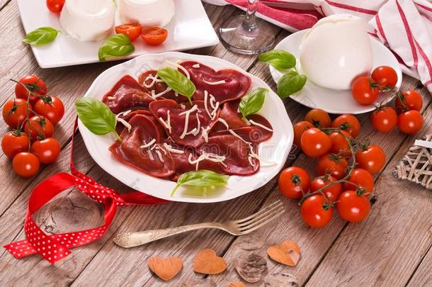 红色的心小方饺和番茄,意大利干酪和罗勒属植物.