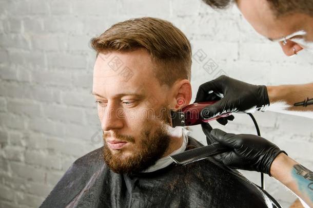 理发师手采用拳击手套将切开头发和刮成熟的总是有胡须的英语字母表的第13个字母