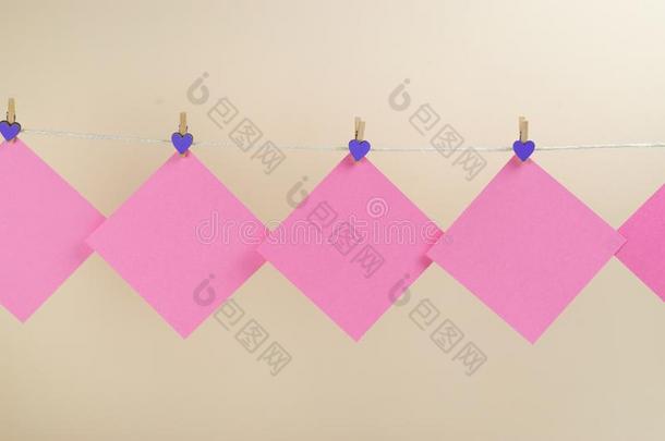 粉红色的有背胶的标签向晒衣绳和晒衣绳上夹衣服之夹子隔离的向白色的