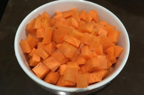 将切开刨切的进入中立方形形状胡萝卜和放进入中白色的碗.