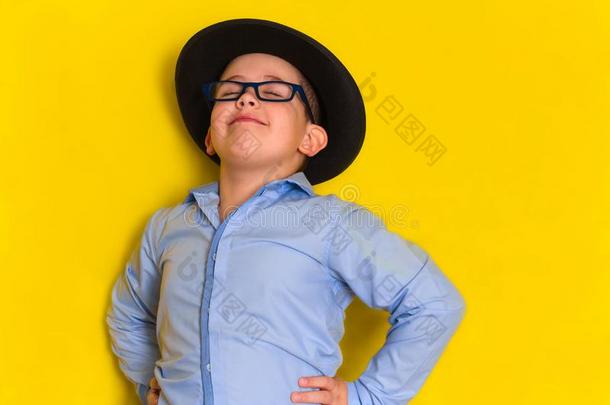 美丽的小的男孩采用帽子和衬衫向黄色的背景