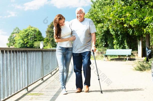 女人帮助她父亲在期间步行采用公园
