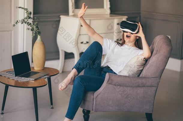 年幼的女人调节她VirtualReality<strong>虚拟现实</strong>戴在头上的耳机或听筒和<strong>微笑</strong>的在期间在家